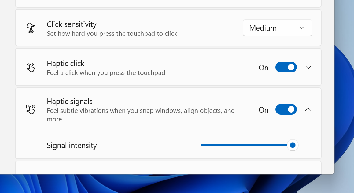 Windows 11 settings interface showing touchpad options: Click sensitivity set to medium, Haptic click and new Haptic signals toggled on, with Signal intensity adjustable.