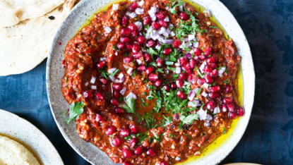 A large plate of Muhammara topped with pomegranate seeds