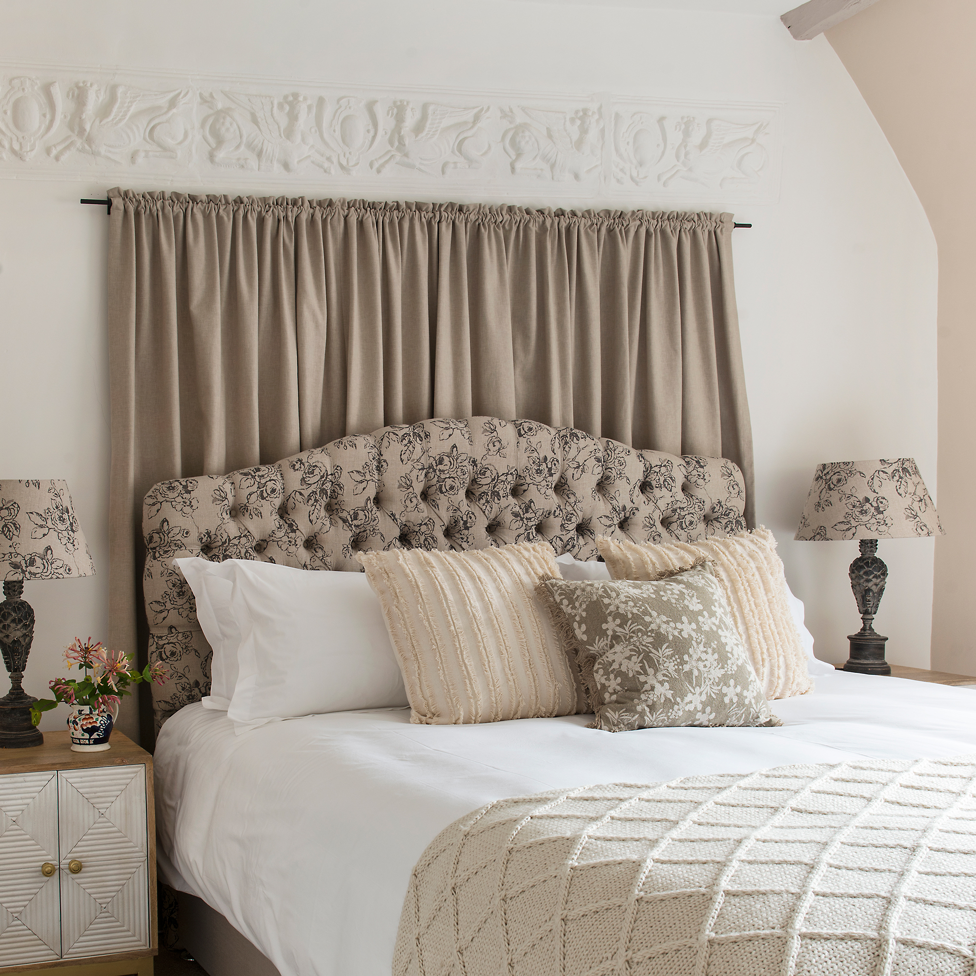beige and neutral bedroom scheme in a cottage with headboard curtain