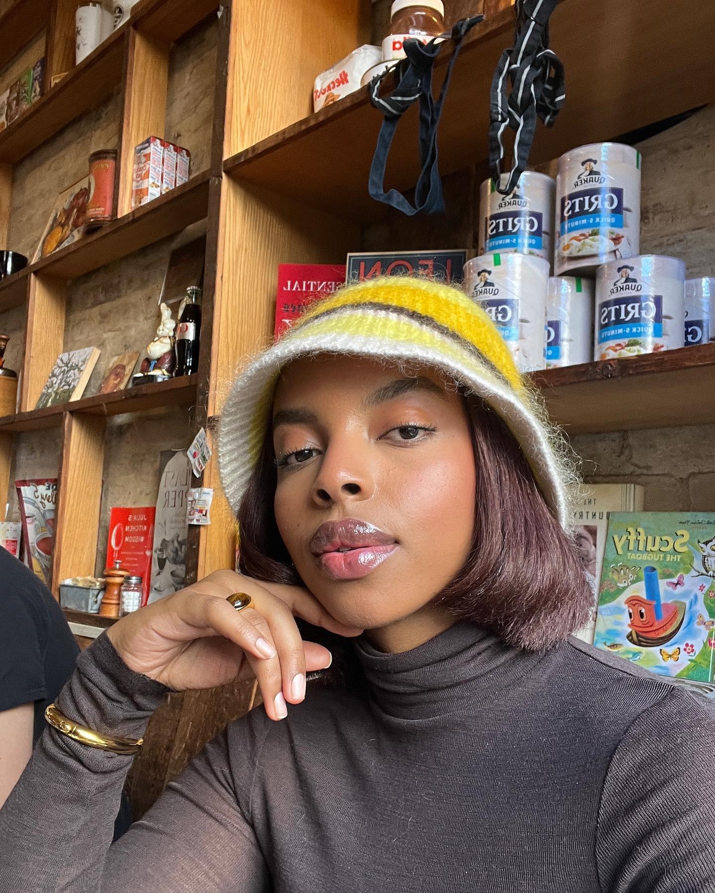 A woman taking a selfie with a disconnected bob, wearing a fluffy striped hat from Cos
