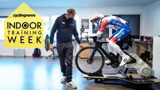 A Groupama FDJ team staff looks at a dummy representing Groupama FDJ cyclist Thibaut Pinot, installed on a time trial bike during a press day at the Groupama FDJ performance center