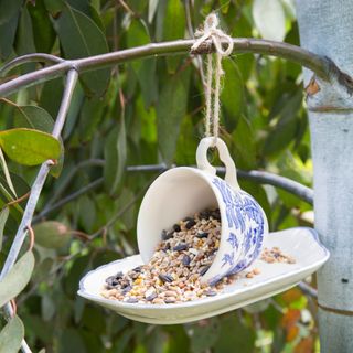 A hanging bird feeder made from a tea cup and saucer