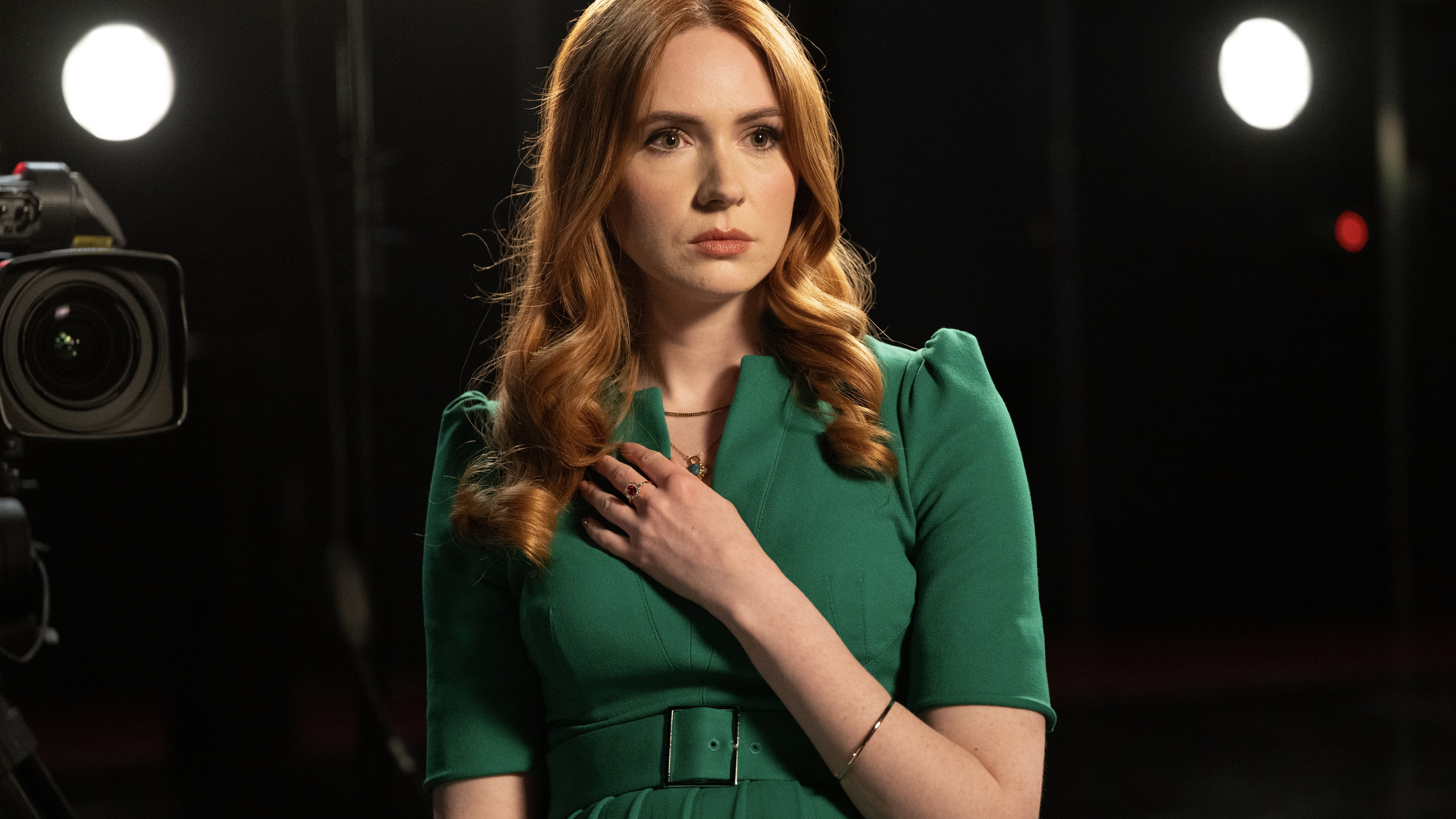 Karen Gillan in a green dress holding her hand over her microphone as Madeline in Douglas is Cancelled