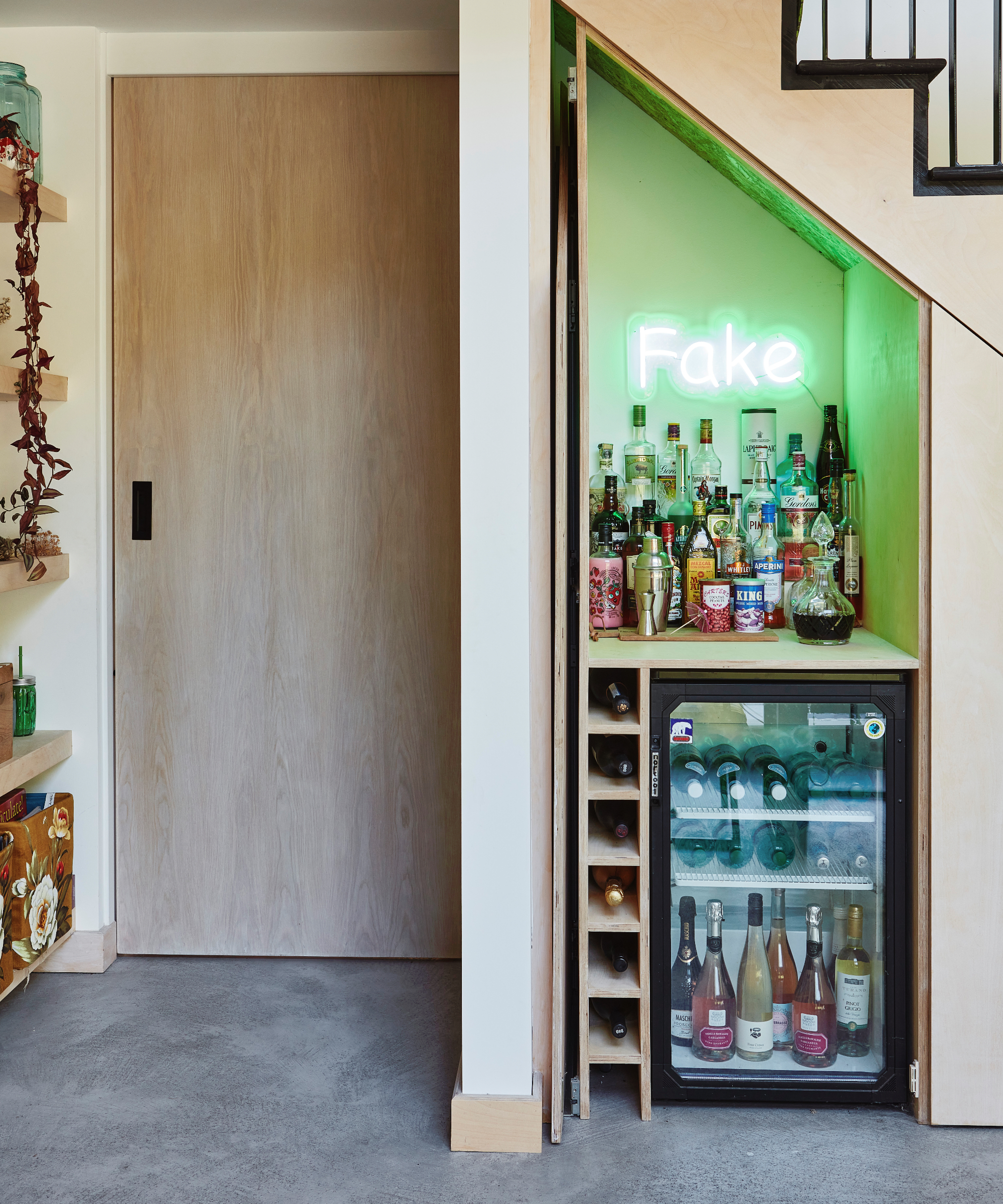 Small home bar under stairs with wine fridge and neon sign