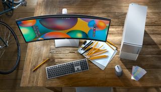 XPS desktop monitor and keyboard sitting on desk with pencils and notebook