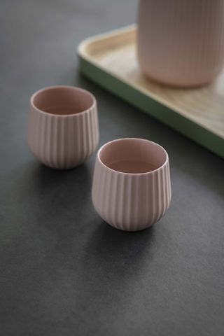 a pair of two fluted tumblers sit on a table top pale pink colour reeded tabletop