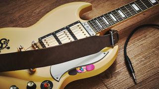 Gibson SG and Leather guitar strap on a wooden floor