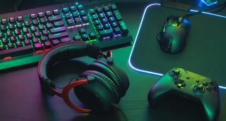 A gaming headset, controller, mouse and keyboard on a desk,