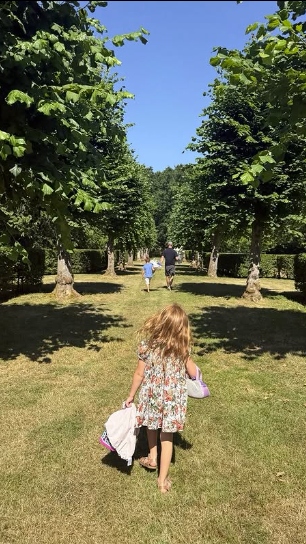 A screenshot of a picture shared by the Duchess of Sussex, showing Prince Harry, Archie and Lilibet walking through tree-lined grounds