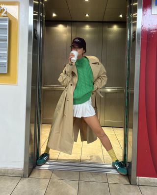 Aimee Song wearing a trench coat and cableknit sweater