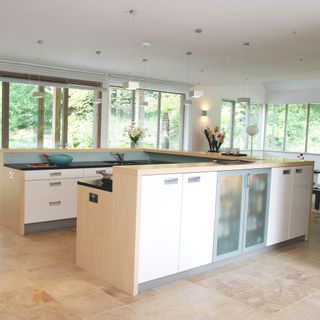 kitchen with white cabinet black counter windows and cream colour tiles flooring