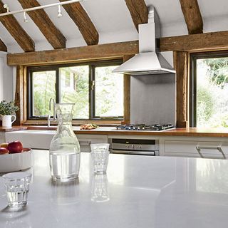 kitchen with white counter wooden beam on window chimney and pot on counter