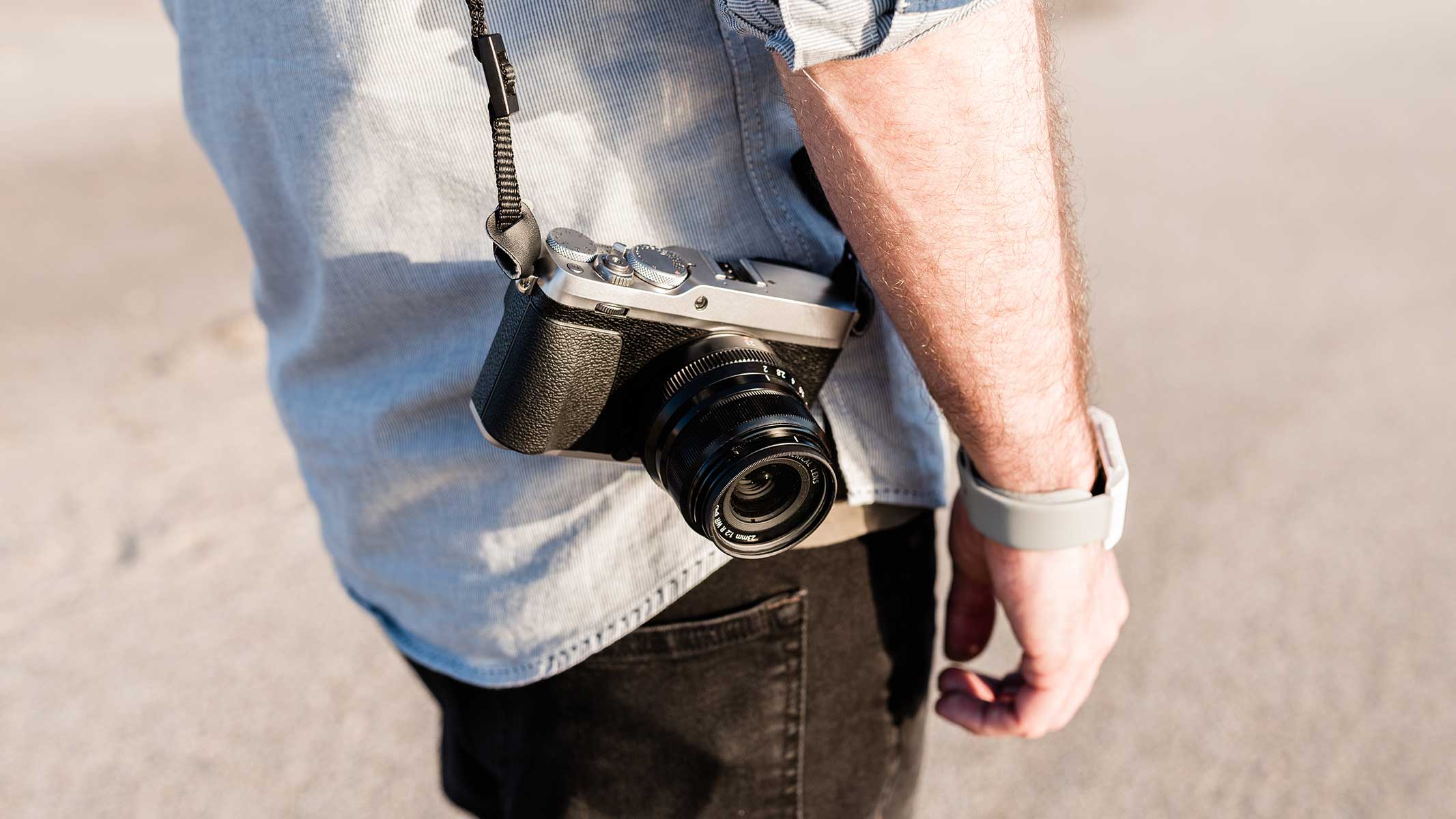 Man with mirrorless camera on strap round shoulder