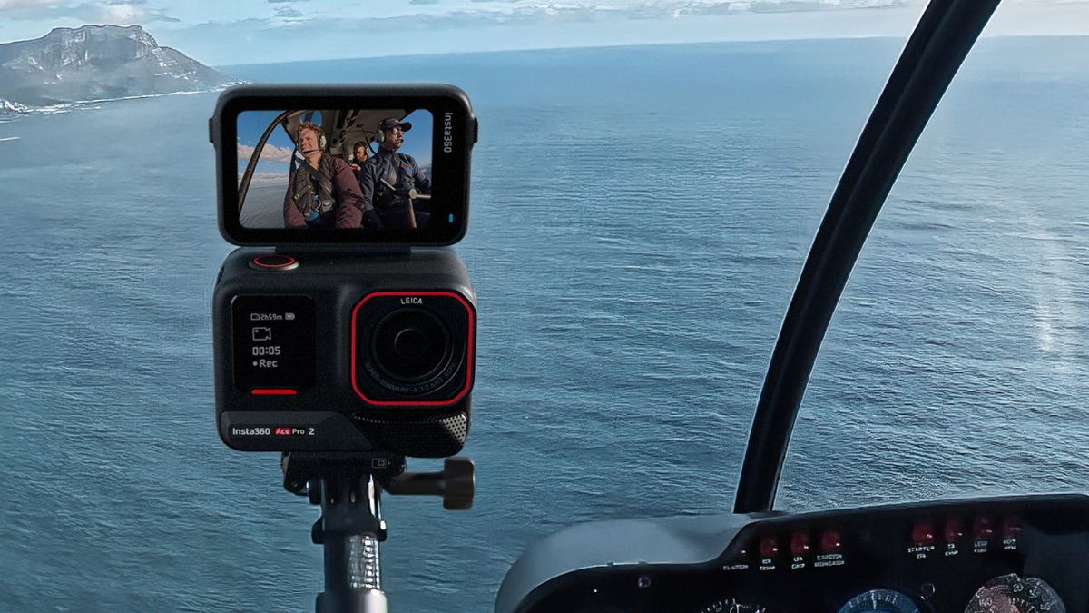 Insta360 Ace Pro 2 camera on a selfie stick in a helicopter front seat, next to the control panel. You can see the pilot and passenger in the camera&#039;s monitor.