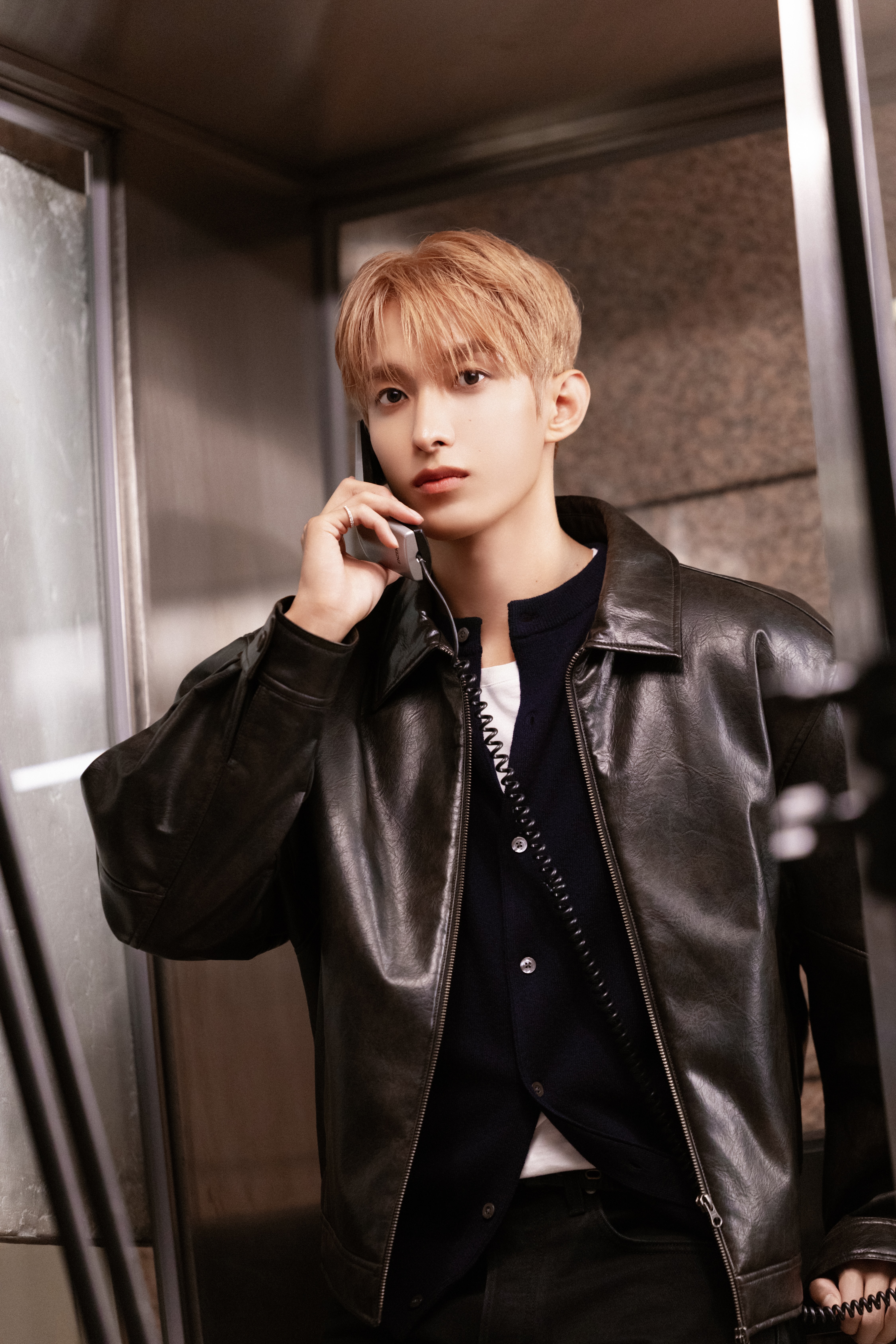 dk from the k-pop group seventeen holds a corded phone up to his ear