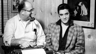 Singer Elvis Presley and his manager Colonel Tom Parker sit at a typewriter