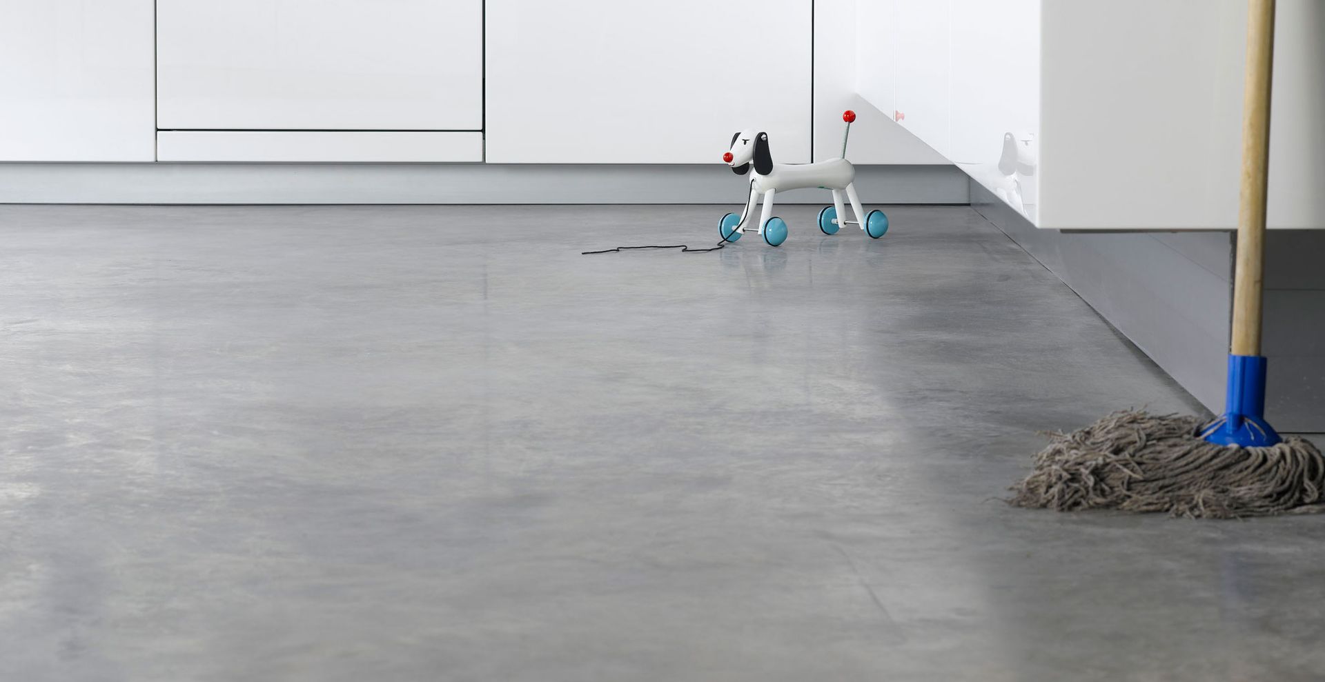 concrete kitchen floor with toy on wheels and mop to ask how often should you mop floors in the kitchen