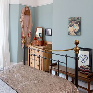 bedroom with blue wall bed wooden drawer and bench