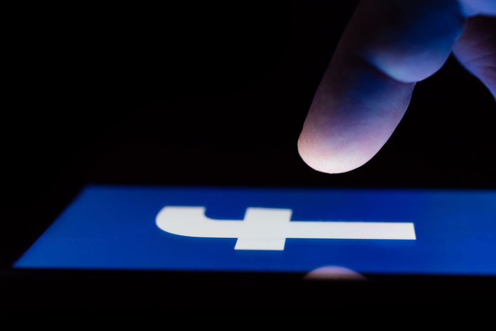 finger above Facebook icon