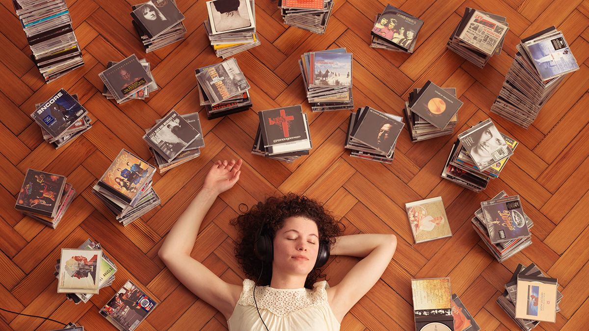 A woman lies on the floor listening to old CDs