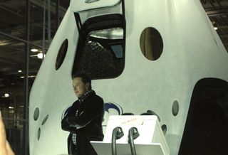 Elon Musk poses with his newest – and most remarkable – achievement, the Dragon Version 2 spacecraft, on May 29, 2014.