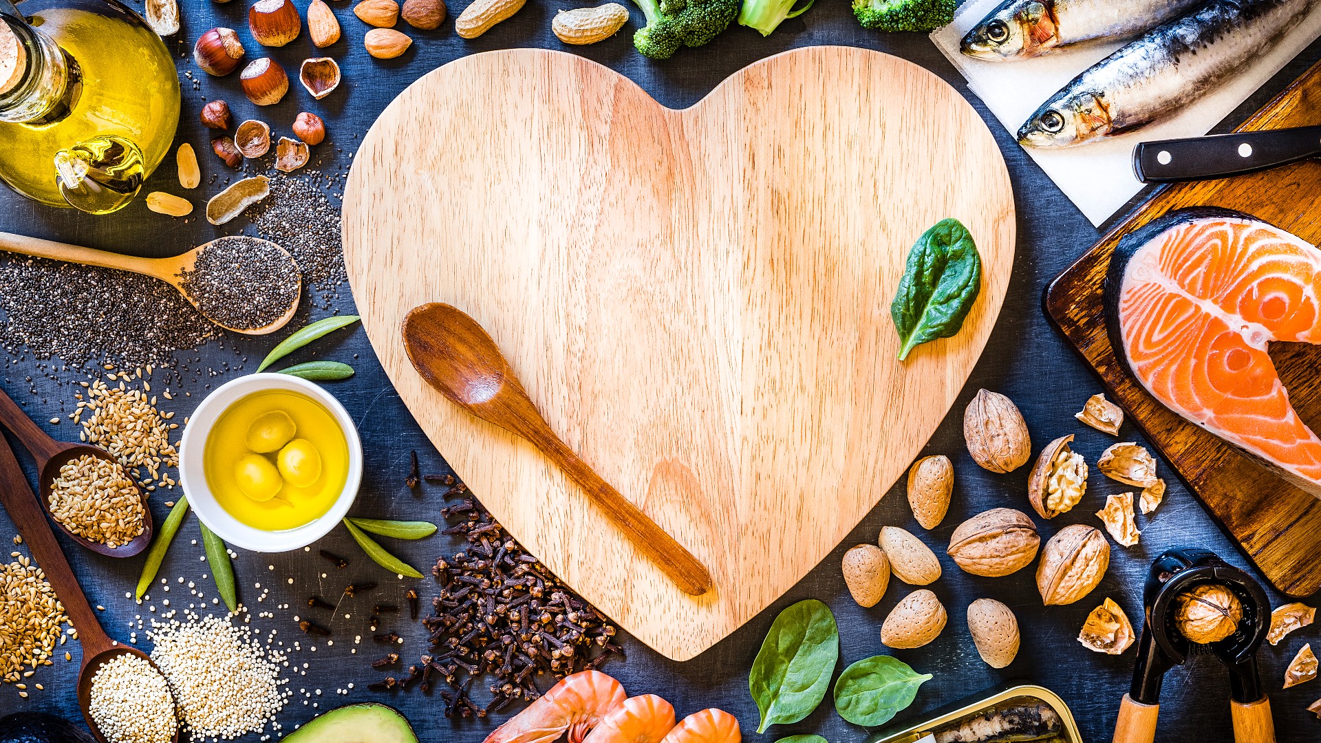 Heart shaped wooden chopping board surrounded by foods rich in omega-3