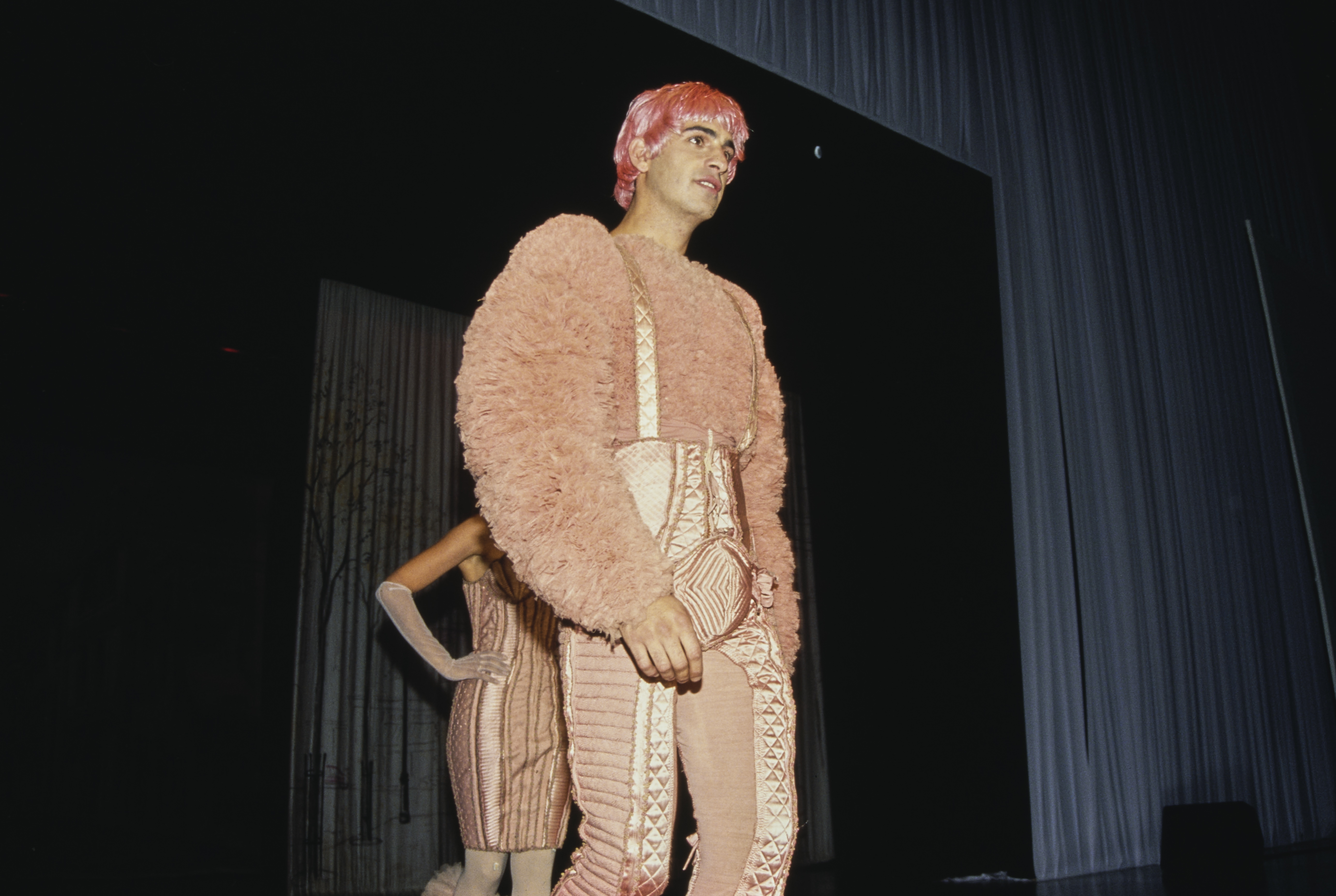 A fashion model walks the runway, wearing a pink outfit with pink hair designed by French fashion designer Jean Paul Gaultier, during a Gaultier fashion show staged at Shrine Auditorium in Los Angeles, California, 24th September 1992. The event was held as a fundraiser for amfAR (American Foundation for AIDS Research). (Photo by Vinnie Zuffante/Getty Images)