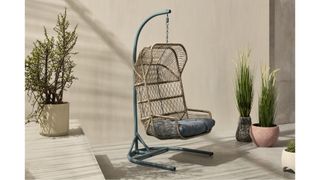 MADE Lyra Garden Hanging Chair in an indoor-outdoor area with lots of plants
