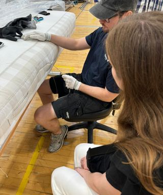 Emilia watching a Hastens craftsman stitch the side of a mattress.