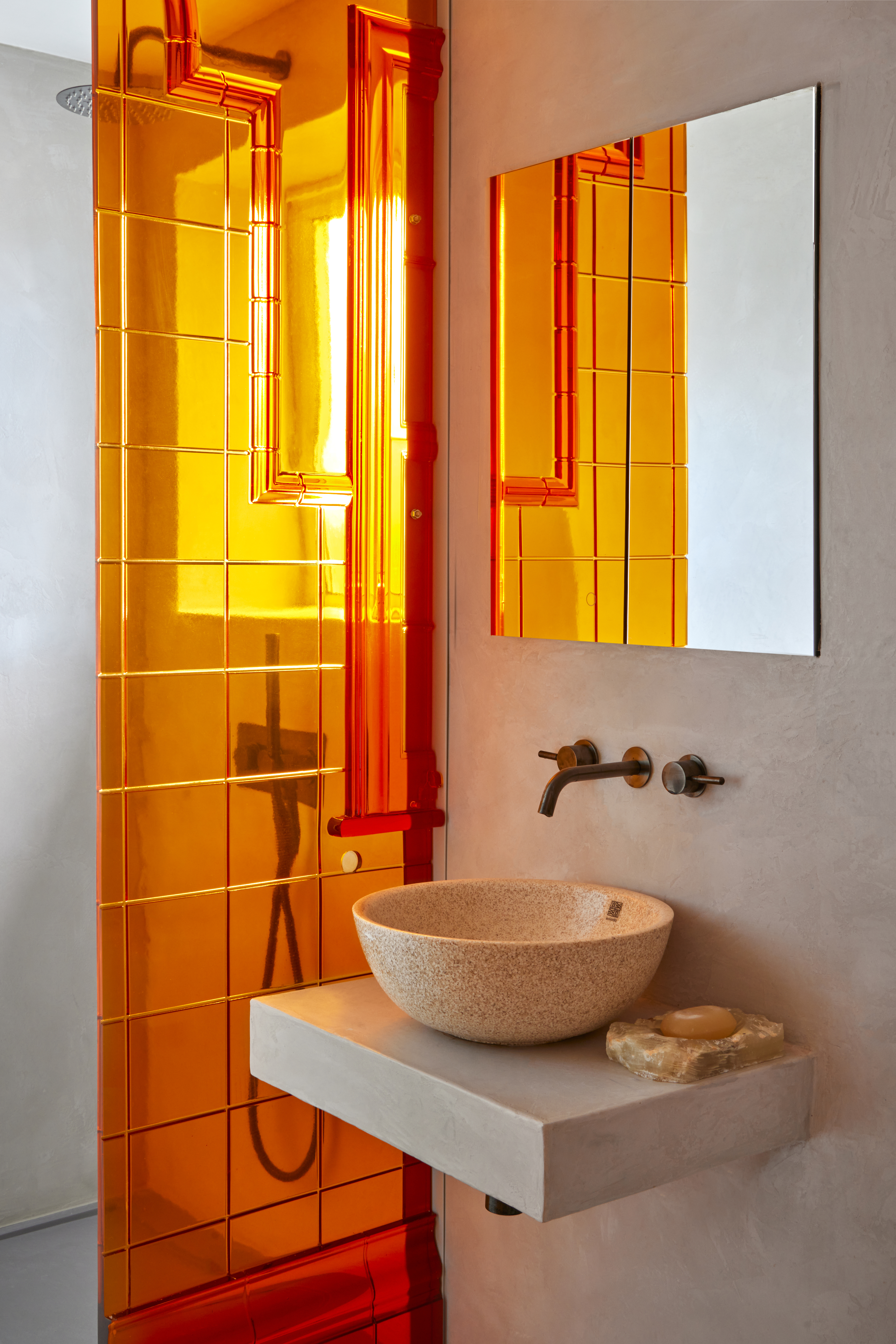A bathroom with a colorful acrylic divider, and a square mirror