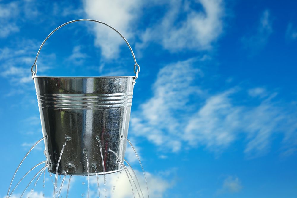 A bucket with holes leaking water 