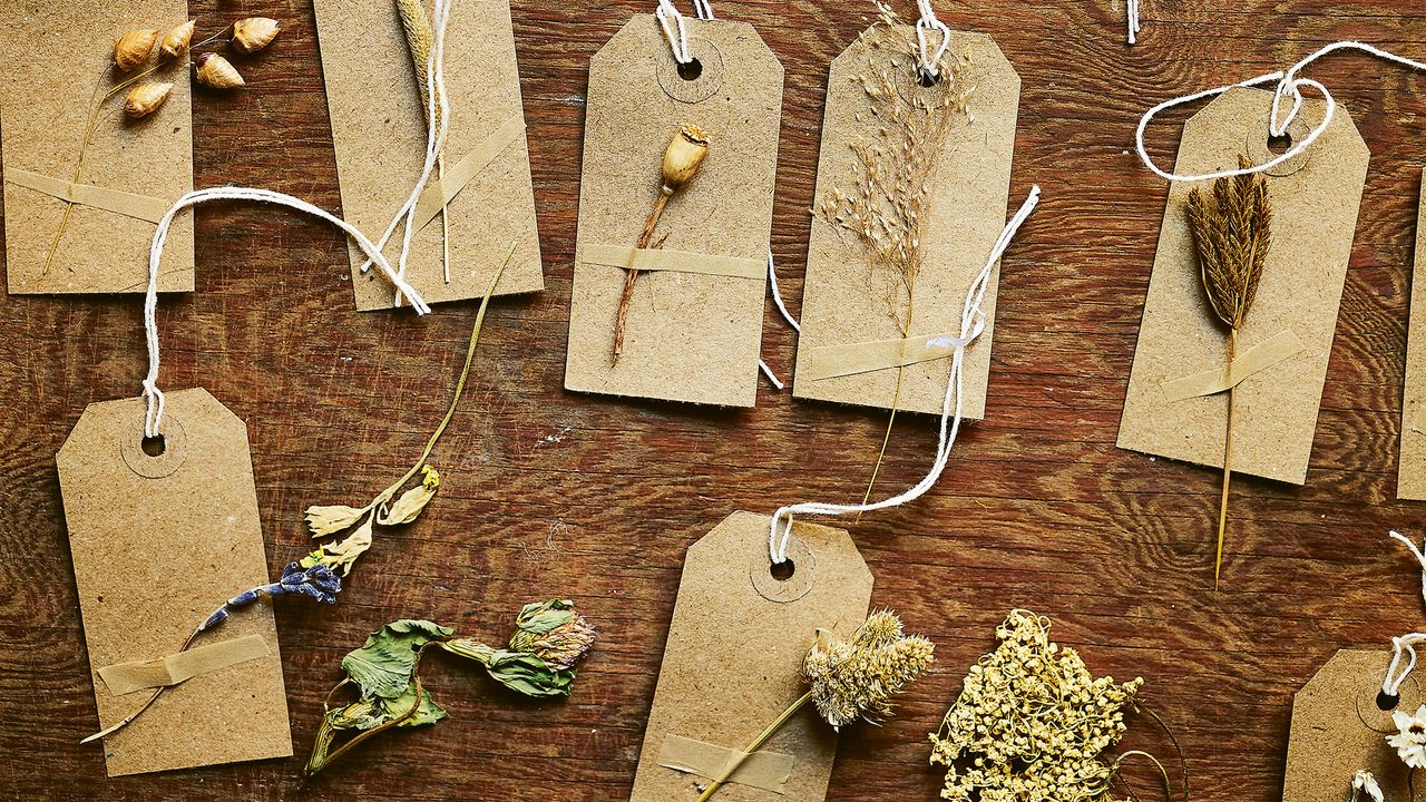 how to make dried flower gift tags. Wooden dining table covered with small brown gift tags decorated with dried flowers