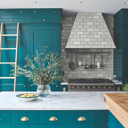 Bold colourful kitchen with light worktops, tiled splashback and extractor hood, and brushed brass handles