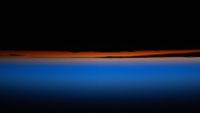 the top portion of the image is black followed by a bright red and orange band of color which blends into an ombre of blue into black at the bottom of the image. 