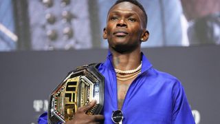 Israel Adesanya of Nigeria poses on stage during the UFC 276 press conference with his UFC belt