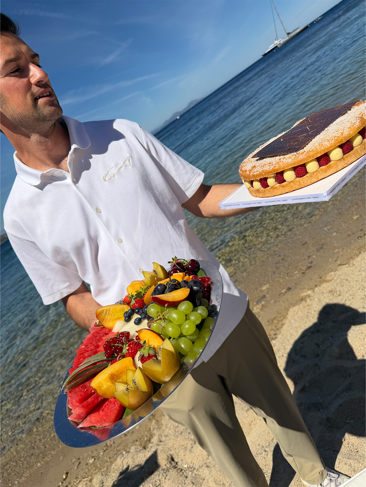 A server bringing over fresh fruit and French cake on the beach.