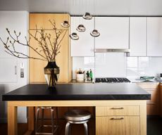 Black topped wooden kitchen island with kitchen behind