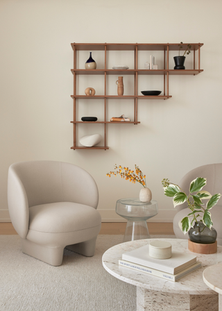 A living room with a wall-mounted shelf a coffee table and chair.