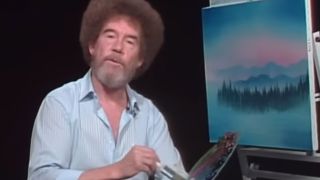 Bob Ross standing in front of a painting, looking at the camera