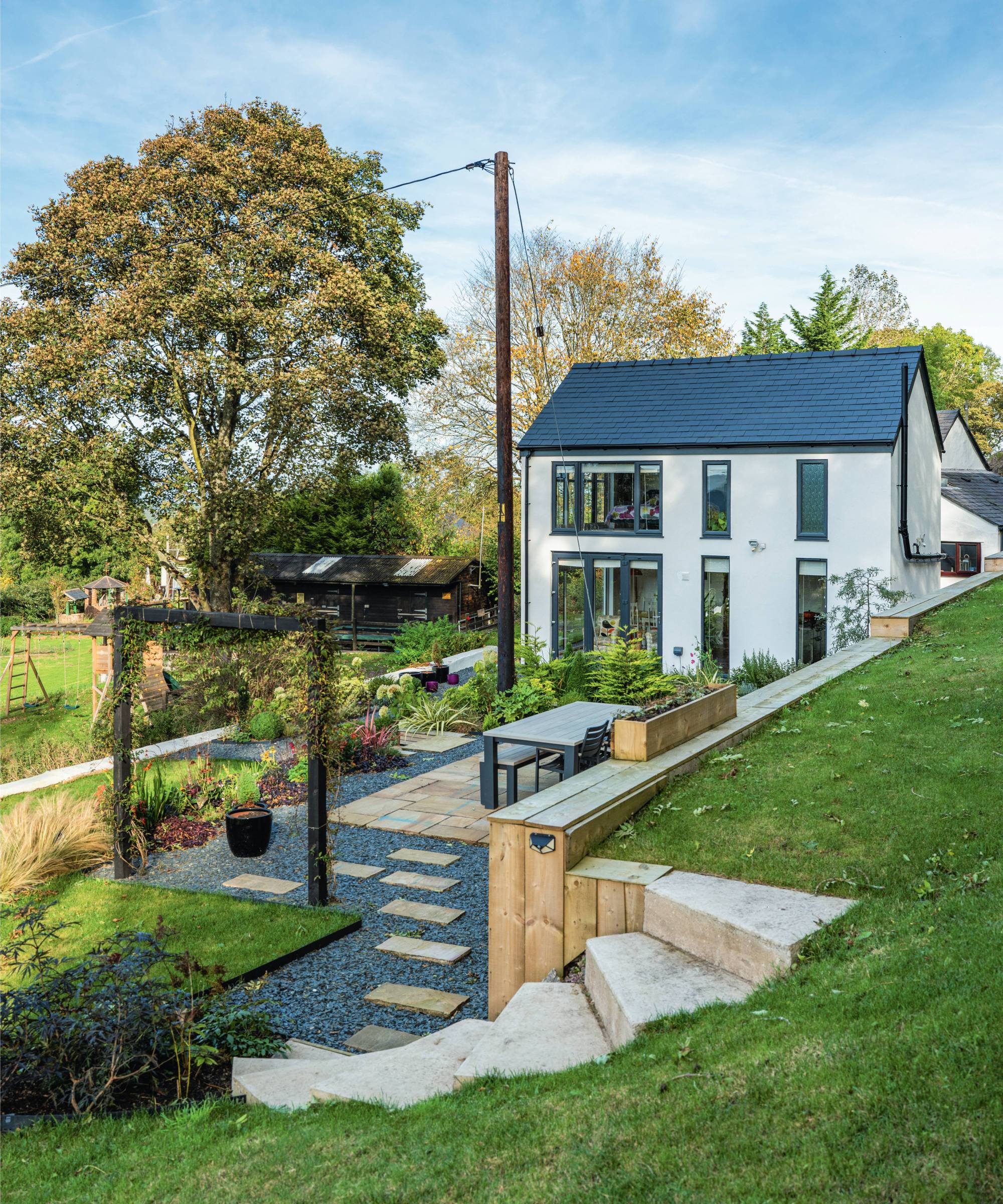 White stone cottage in Welsh countryside with modern extension and gravel and stepped landscaping