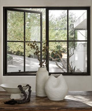 A black-framed window with a vase of flowers