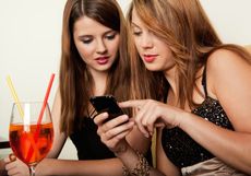 Two women have a drink and look at a smartphone