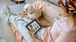 Woman shopping online with dog next to her