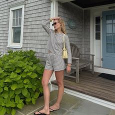 Influencer Lauren Nelson wears a striped set with a butter yellow bag and black flip flop. 