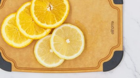 A light brown paper fiber cutting board with fresh lemon slices on top of it 