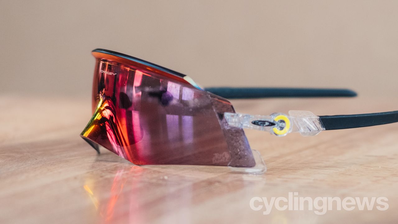A red pair of sunglasses sits on a wooden tabletop