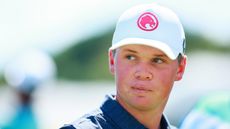 Caleb Surratt during a LIV Golf event wearing a white cap and navy polo