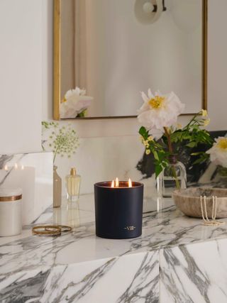scented candle inj black glass vessel on marble worktop