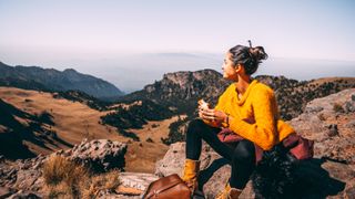 A hiker eating a sandwich and enjoying the view
