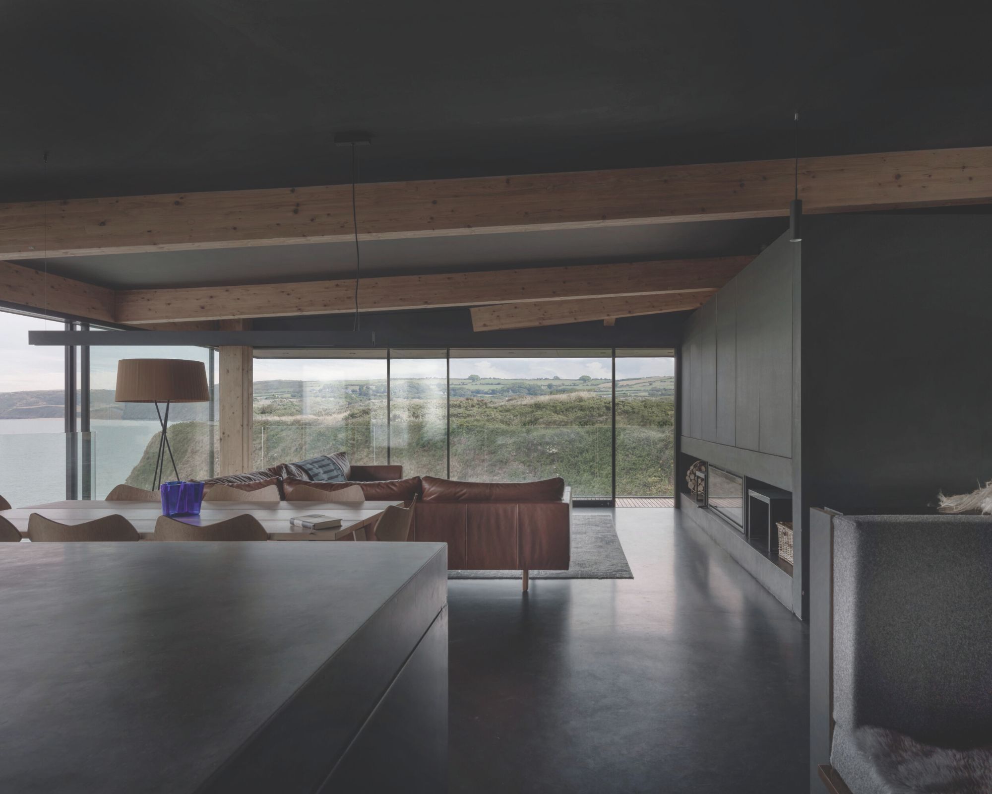 An ultra-modern sitting room with glass walls and views out to sea